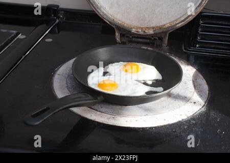 Two hen's eggs frying in a pan on an aga stove Stock Photo