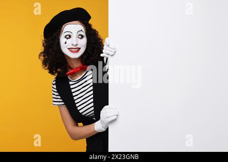 Funny mine with blank poster posing on orange background, space for text Stock Photo