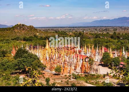 The pagoda forest of In-Dein on Burmese's Inle Lake shows many ring-shaped tapered stupas Htis in the flat landscape of Inle Lake, Myanmar, Southe Stock Photo