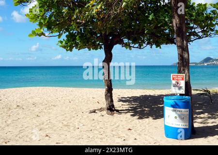 Garbage trash can with warning board, do not litter, on a romantic sandy beach with azure blue sea in Castries, Saint Lucia. Stock Photo