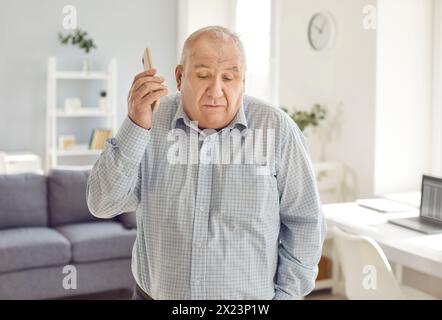 Elderly Man Looking Puzzled Talking On The Phone At Home Stock Photo