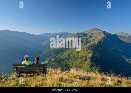 Man and woman hiking sitting on bench and looking at Gilfert, Kuhmesser, Tux Alps, Tyrol, Austria Stock Photo