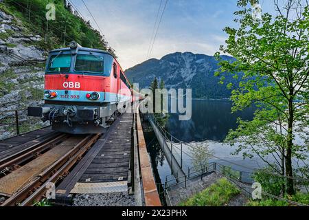 Train runs along Lake Hallstatt, Dachstein in the background, Salzkammergutbahn, Salzkammergut, Upper Austria, Austria Stock Photo
