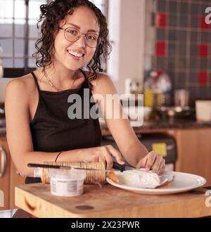 Happy girl, portrait and breakfast with cheese, crackers or spread for healthy meal, diet or snack in kitchen at home. Face of young woman with smile Stock Photo