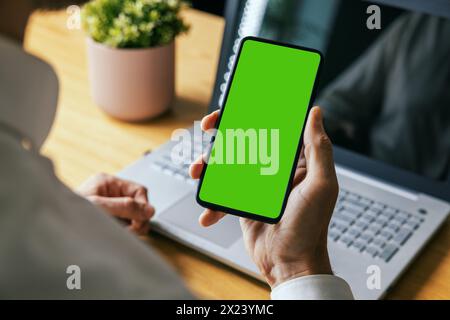 man holding mobile phone in hand with blank green screen. mockup template Stock Photo