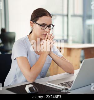 Thinking, female person and developer in office with laptop for vision to planning, solutions and ideas for a creative startup business. Woman Stock Photo