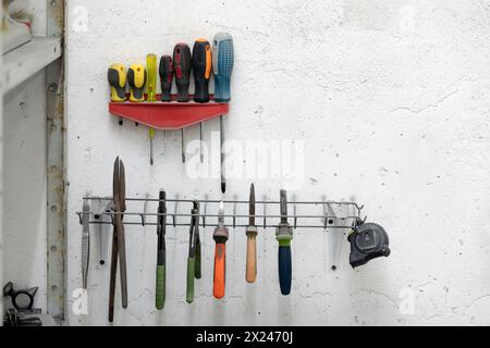 Screwdrivers and other tools hanging on a wall in a workshop Stock Photo