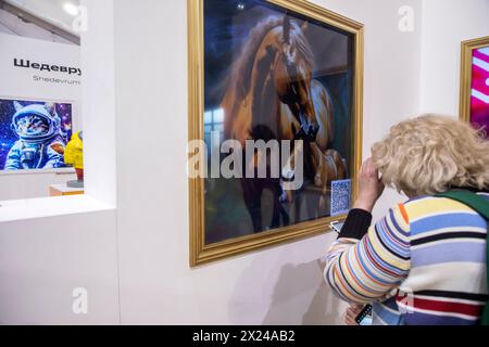 Moscow, Russia. 19th of April, 2024. Visitors to an exhibition watch paintings generated by the Shedevrum AI app of Yandex IT company, on the territory of the Yandex stand at the VDNKh exhibition complex in Moscow, Russia Stock Photo