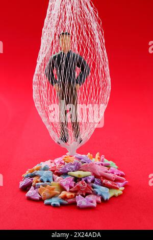 Man caught in his own net on colorful piled up fish Stock Photo