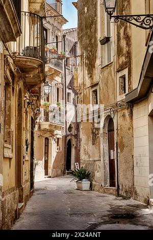 A narrow street on the island of Ortygia in Siricusa, Sicily is deep in shadow. Stock Photo