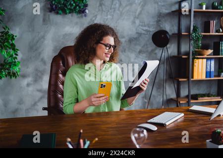 Photo of nice lovely glad woman reading paper list cv resume in modern office room workspace workstation Stock Photo