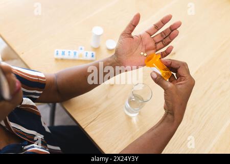 African American senior woman is pouring pills into her hand at home Stock Photo