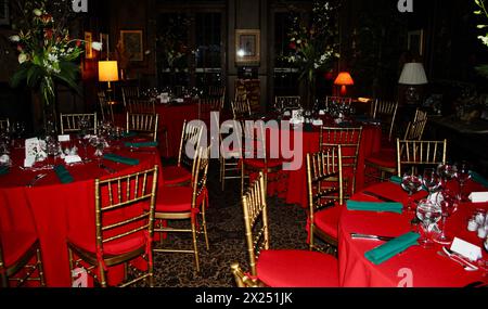 Dinner tables with red tablecloths, green napkins and gold ballroom chairs at a catered Christmas dinner event in New York City, USA Stock Photo