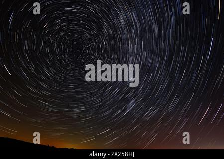 Circular star trails in the sky with a tint of city light from far away on the horizone Stock Photo