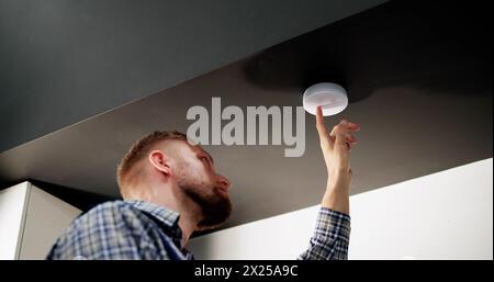 Installing Smoke Detector On Ceiling At Home Stock Photo