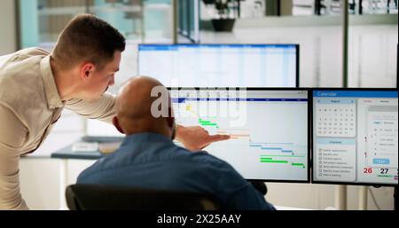 Young Businesspeople Analyzing Gantt Chart And Calendar On Computer In Office Stock Photo