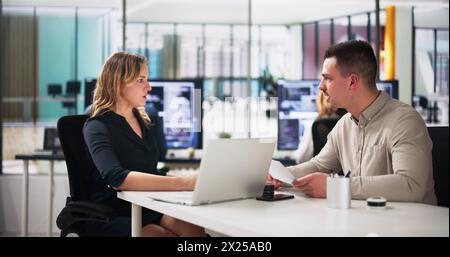 Young Happy Businesspeople Talking With Each Other In Office Stock Photo