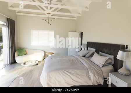 Senior woman relaxing on bed, dog sleeping in cozy bed nearby, in bright bedroom Stock Photo