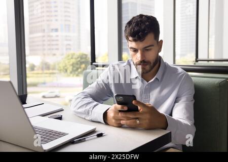 Serious young Arab businessman typing on smartphone on job chat Stock Photo