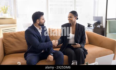 Two happy diverse businesspeople shaking hands at co-working workplace Stock Photo