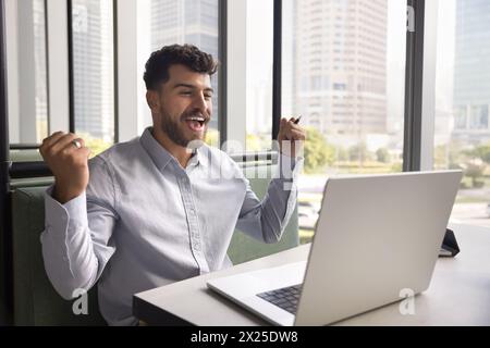 Happy joyful Arab business man enjoying win, victory Stock Photo