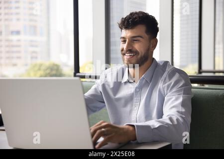 Happy young Arab freelance business man typing on laptop Stock Photo