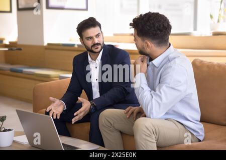 Confident young Indian business man presenting project on laptop Stock Photo