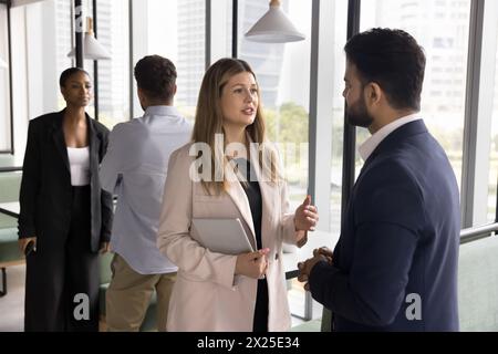 Couple of multiethnic colleagues talking, discussing work project Stock Photo