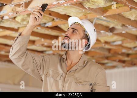 builder using smartphone to photograph ceiling joists Stock Photo