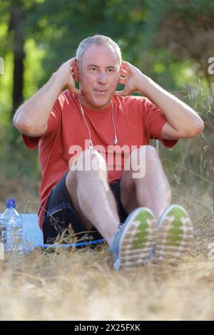 serious middle-age sportsman doing sit-ups outdoors Stock Photo