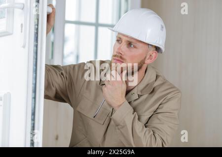 young handsome builder thinking about something while holding clipboard Stock Photo