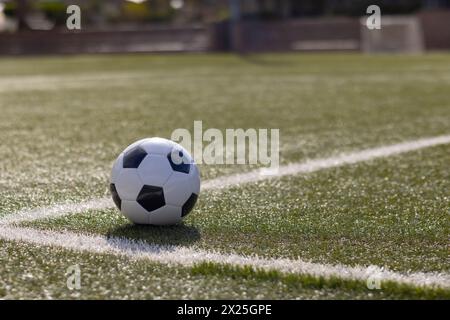 A soccer ball resting on green artificial turf near white line on field outdoors, copy space Stock Photo