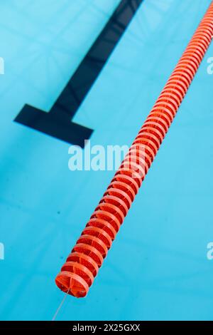A red and white lane divider floats in an indoor blue swimming pool, copy space Stock Photo