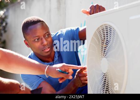 HVAC technician installing air conditioner for optimal comfort Stock Photo