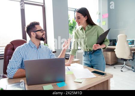 Photo of busy positive coworkers wear shirts talking new working aims indoors workplace workstation Stock Photo