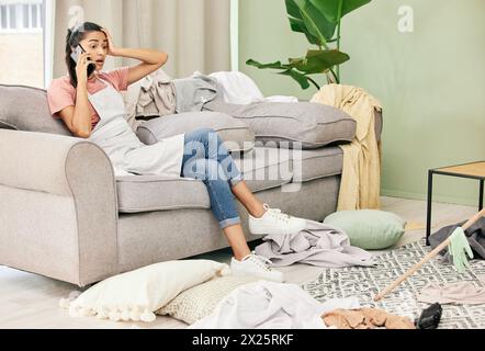 Woman, phone call and stress with cleaning in home for communication, bad news and surprised on sofa. Housewife, smartphone and shocked for gossip Stock Photo