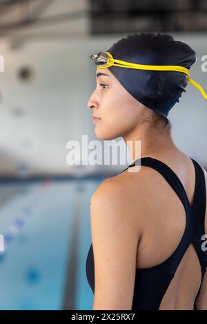 A biracial young female swimmer holding an American flag stands ...