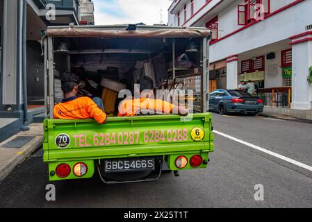 Two men sitting in the back of a truck parked in Singapore Stock Photo