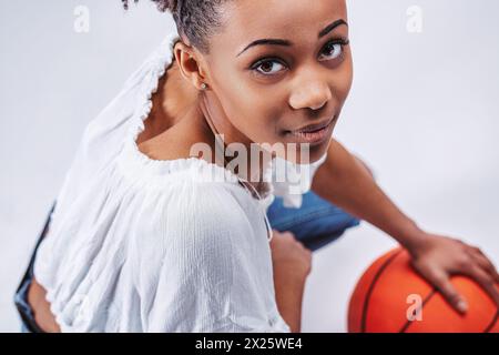 Young, athletic woman gripping a basketball, her determined gaze showing focus and competitive spirit Stock Photo