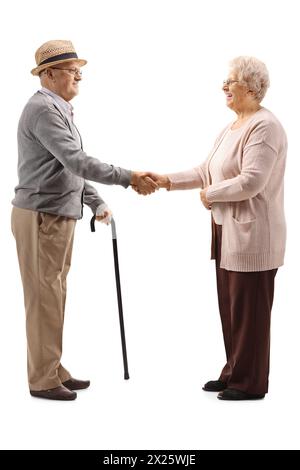 Full length profile shot of an elderly man and an elderly woman shaking hands isolated on white background Stock Photo