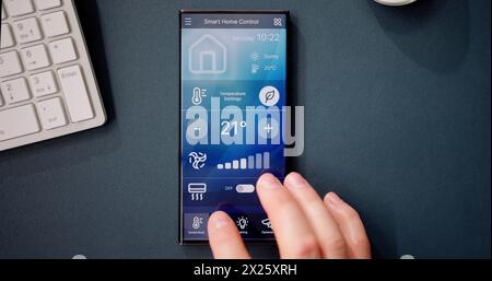 Hand Using Mobile Phone With Home Control System On Screen Stock Photo