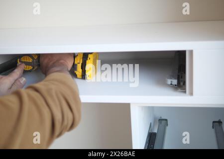 Man installing wooden shelves on brackets wall installing a shelf Stock Photo