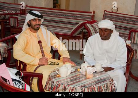 Doha, Qatar.  Two Emirati Arabs from Abu Dhabi, one of African Descent,  Relaxing in a Coffee Shop in the Doha Market. Stock Photo