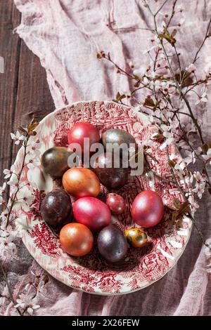 A composition of eggs painted in different colors and covered with mother of pearl, and flowering plum branches. Easter concept, selective focus. Stock Photo