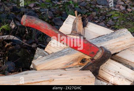 Close-Up Of red Axe On Wood. An old red shabby axe on a pile of firewood.Close-up of axe blade in a wood. Stock Photo