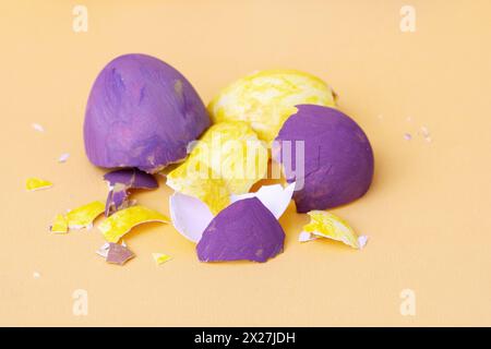 Purple and yellow egg shells from chicken eggs on paper yellow background. Easter concept. Stock Photo