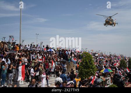 Mosul, Iraq. 20th Apr, 2024. A military helicopter flies low as people attend Spring Festival events in the celebration area of the city of Mosul, northern Iraq. The festival is being held for the second year in a row since it stopped for two decades after 2003 due to the US invasion on Iraq. Spring celebrations go back to the era of the Assyrians, who celebrated the spring season and the beginning of the Assyrian year Akitu. The beginning of this festival in Mosul was in 1969 AD. (Photo by Ismael Adnan/SOPA Images/Sipa USA) Credit: Sipa USA/Alamy Live News Stock Photo