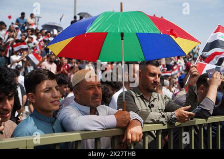 Mosul, Iraq. 20th Apr, 2024. Iraqi men cover themselves with umbrellas during Spring Festival activities in the celebration area in the city of Mosul, northern Iraq. The festival is being held for the second year in a row since it stopped for two decades after 2003 due to the US invasion on Iraq. Spring celebrations go back to the era of the Assyrians, who celebrated the spring season and the beginning of the Assyrian year Akitu. The beginning of this festival in Mosul was in 1969 AD. (Photo by Ismael Adnan/SOPA Images/Sipa USA) Credit: Sipa USA/Alamy Live News Stock Photo