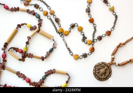 Set of Brazilian handmade necklaces on white background. Female fashion pieces with carved in wood pendant and brown and yellow beads. Stock Photo