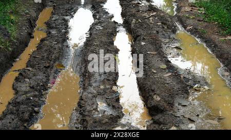 Road in forestry with muddy ruts with water and puddles in rural area ...
